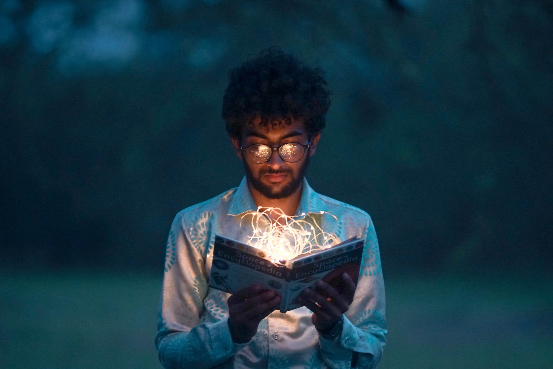 Man looking at open book with fairy lights in it
