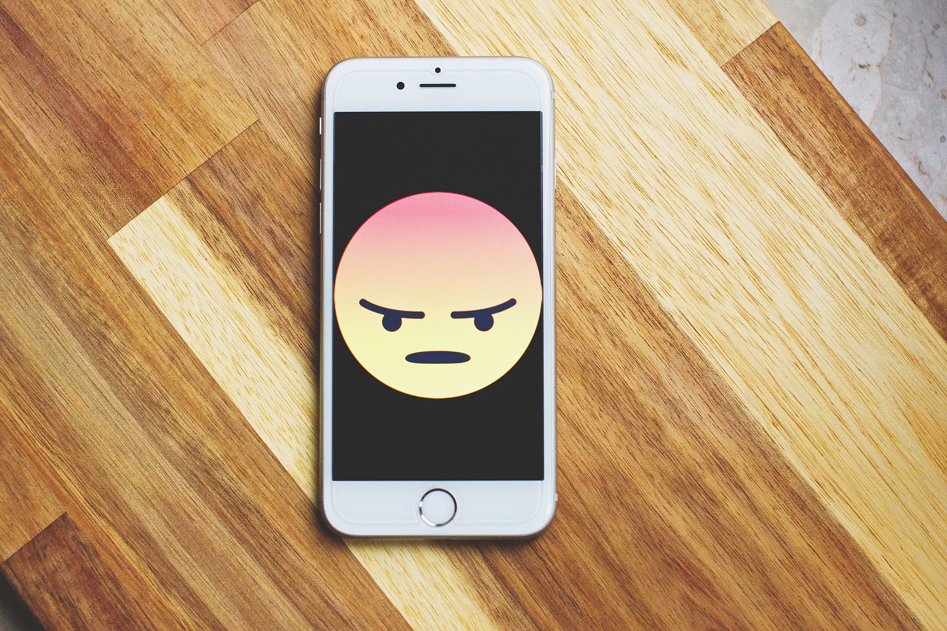 Smartphone with angry face emoji on the screen