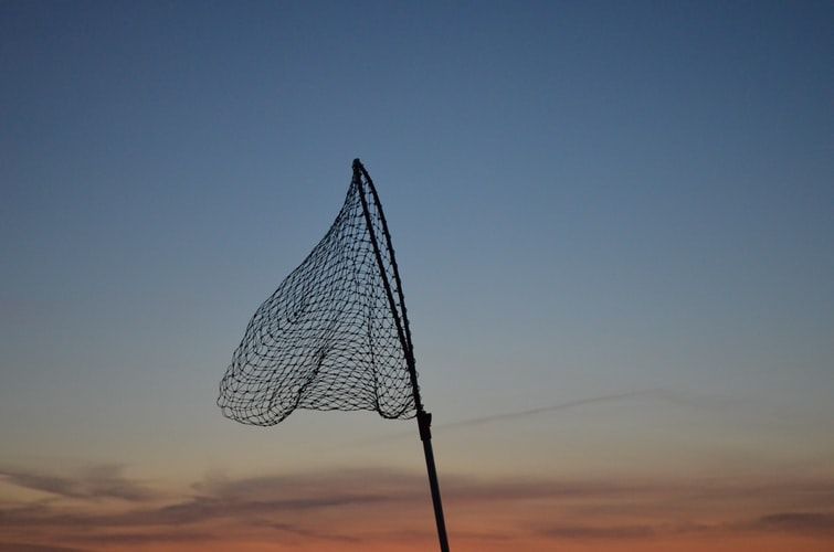 Fishing net held up against the sky 