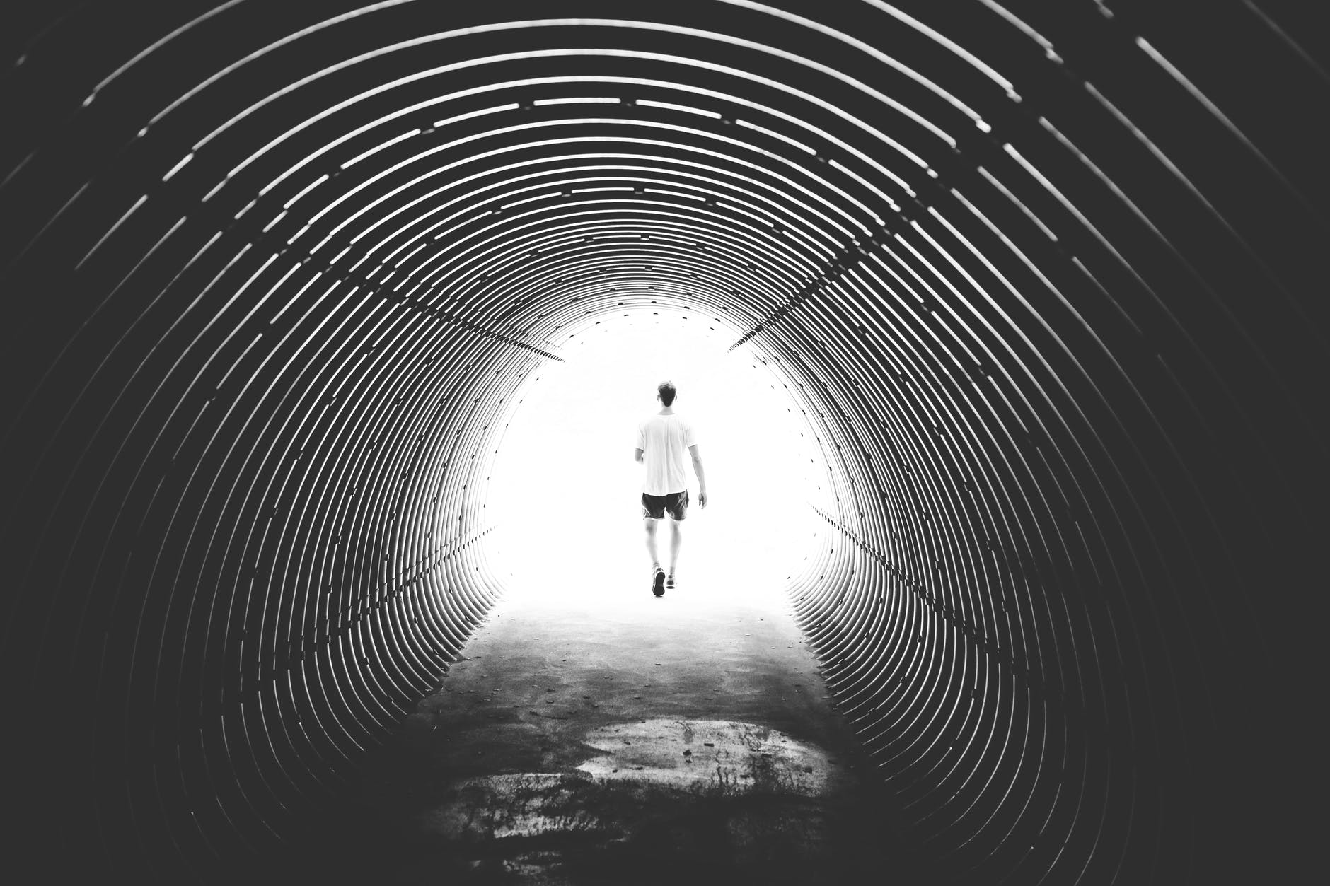 Person walking through a tunnel into the light