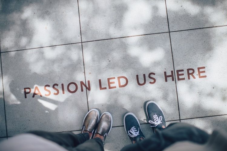 Feet standing by wording on a floor that says 'passion led us here'