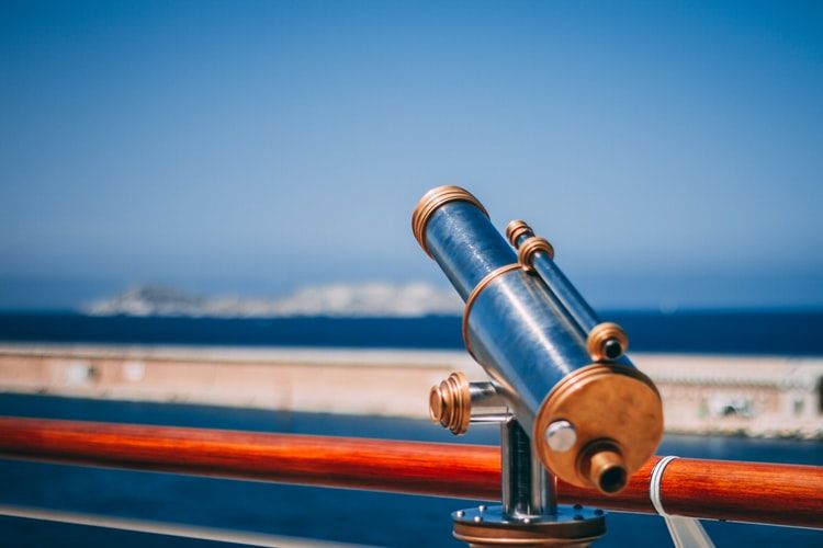 Telescope mounted on rail pointing at the ocean