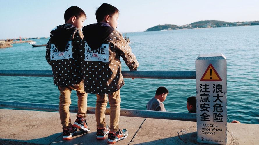 Twin boys in matching outfits looking out over water
