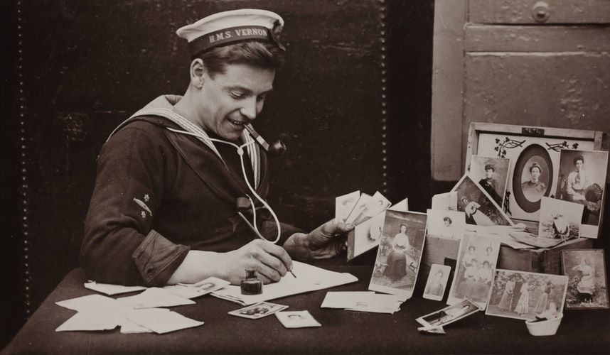 Vintage sailor writing letters home surrounded by photographs