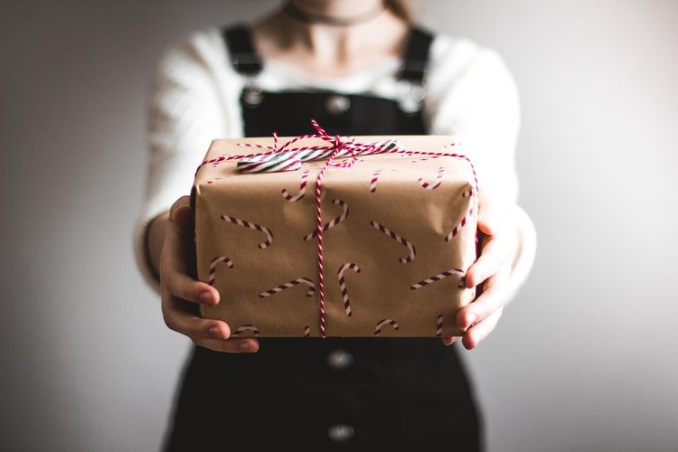 Woman holding out gift wrapped parcel