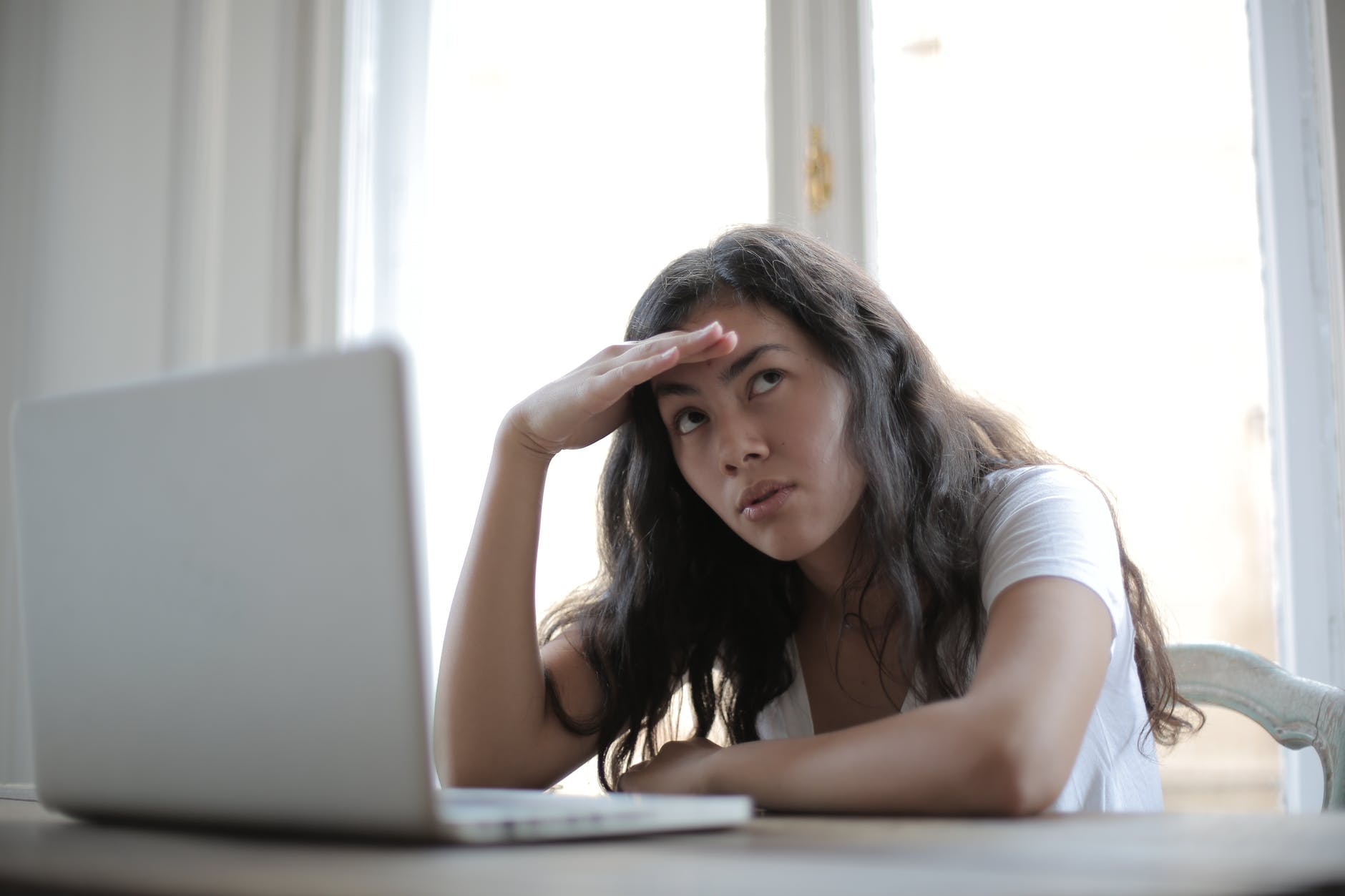 Woman sitting at laptop looking annoyed