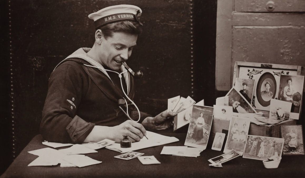 Sailor writing letters while surrounded by family photographs