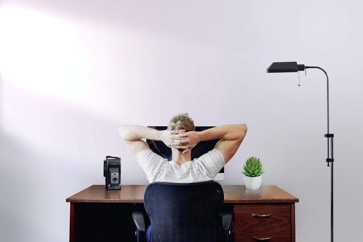 Man sitting at a desk with his hands behind his head