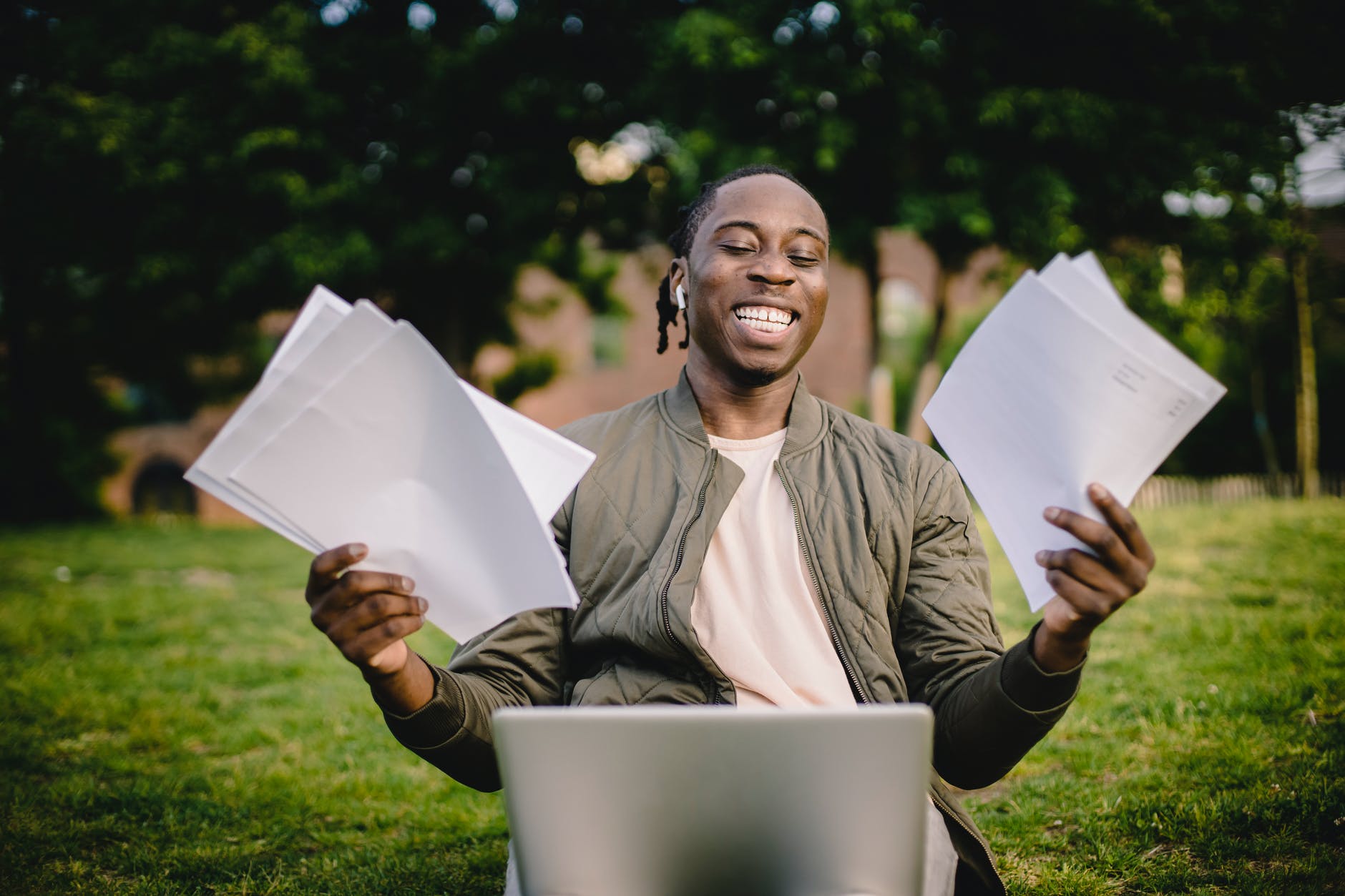 Smiling man looking at laptop and holding sheets of paper