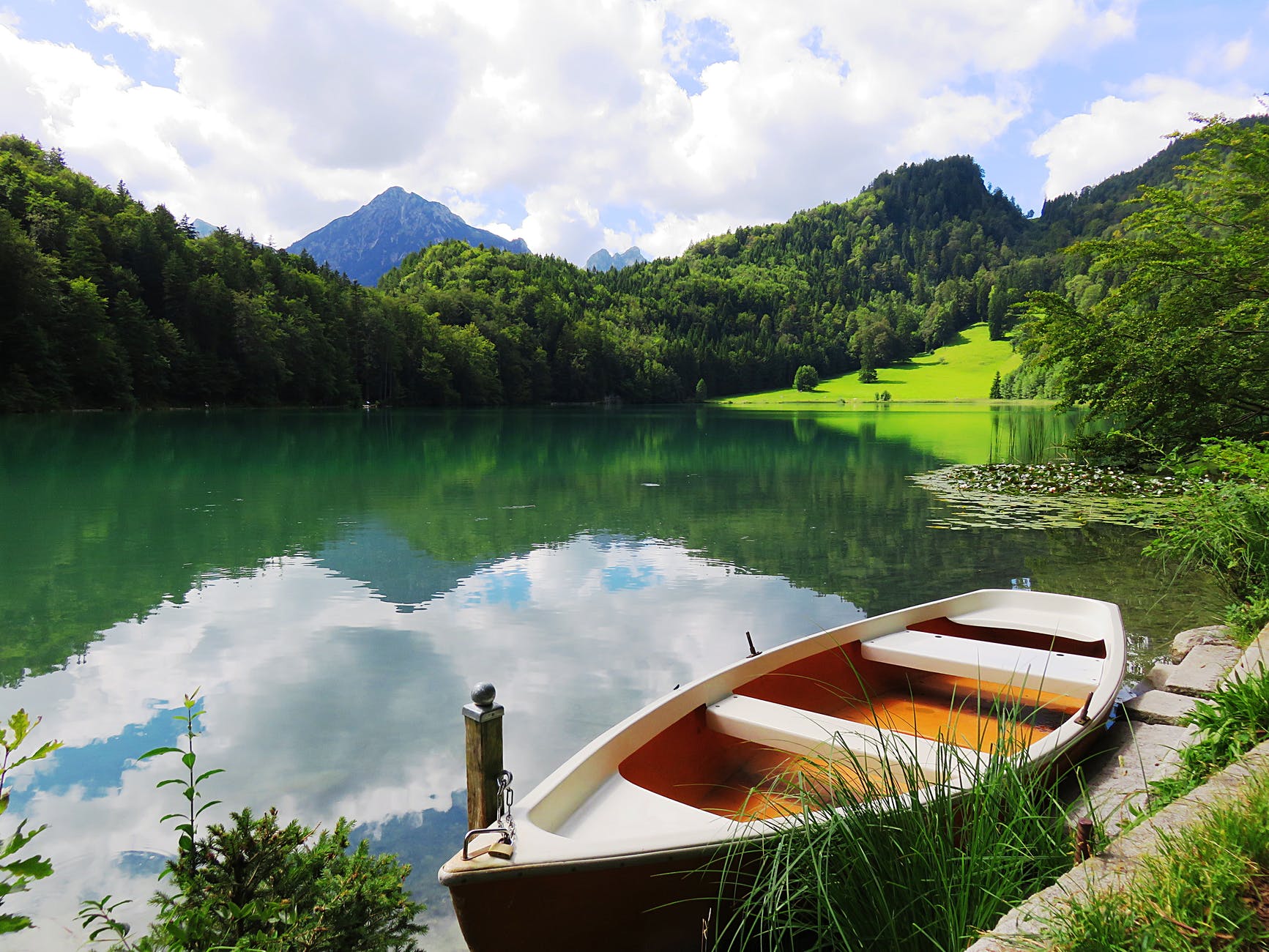 A rowing boat on a placid lake surrounded by mountains