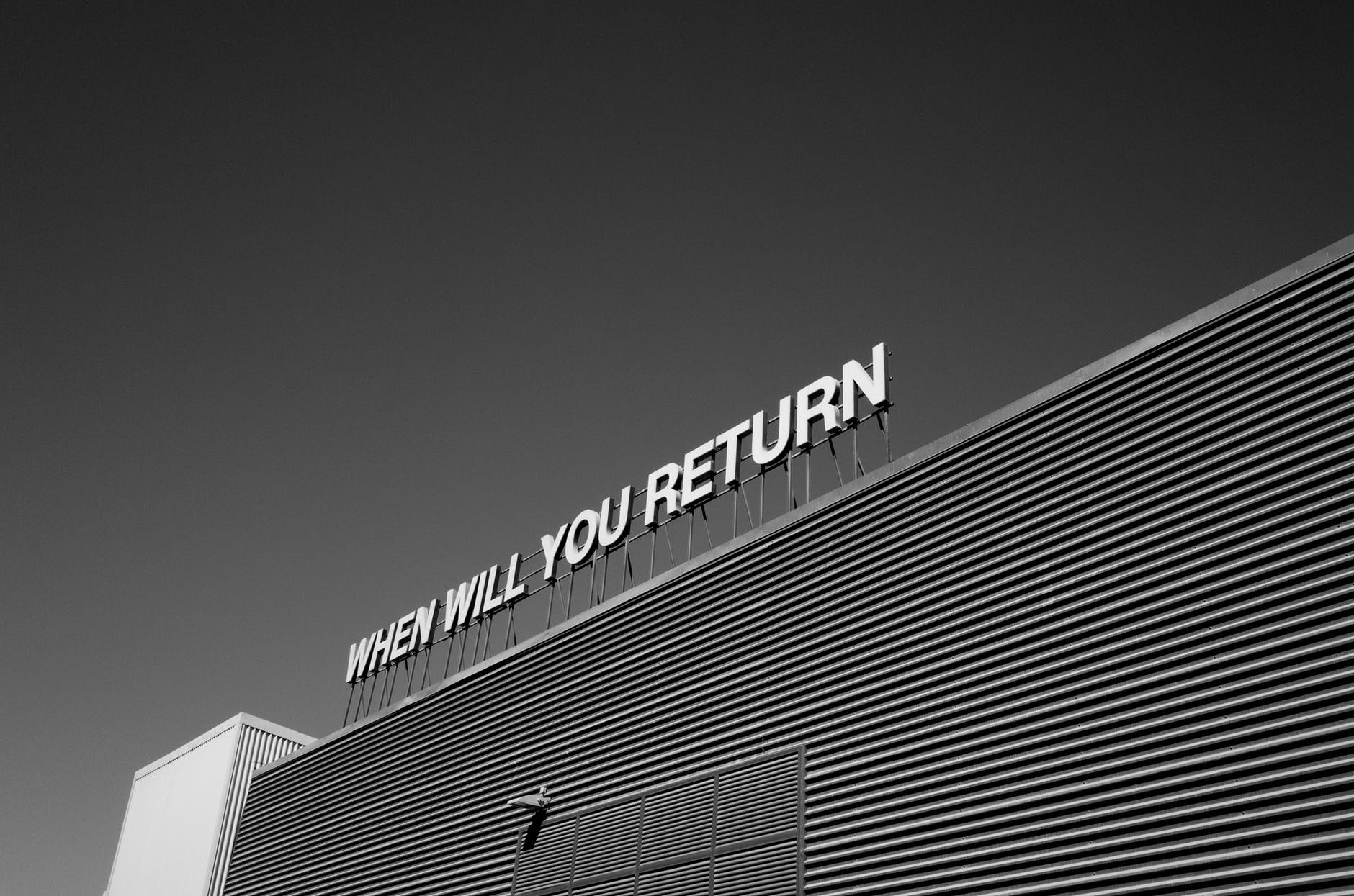 Sign on the roof of a building saying 'when will you return'