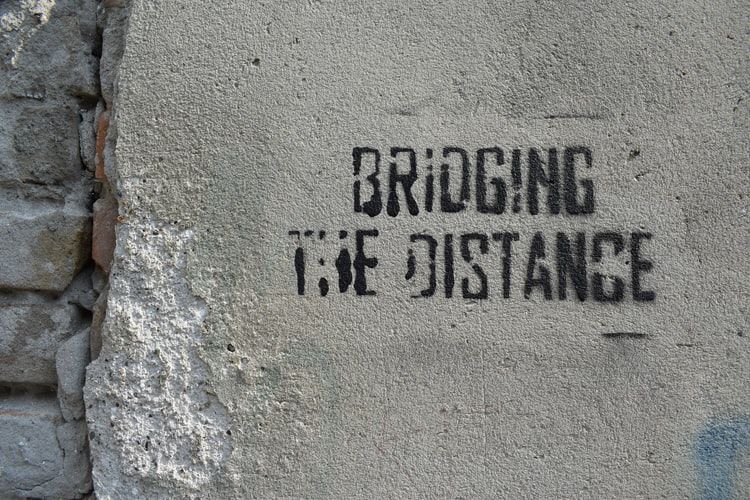 Stencil on concrete saying 'bridging the distance'