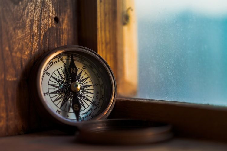 A nautical compass propped up against a window