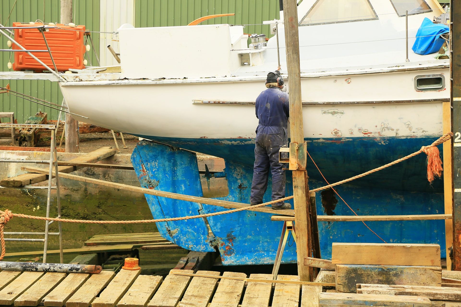 A man on a dock performing maintenance on a boat