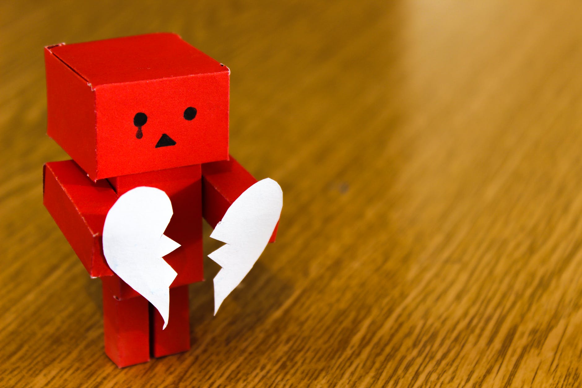 A cardboard robot holding a paper broken heart