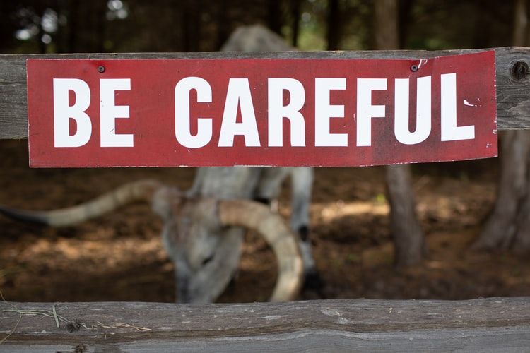 Red wooden sign saying 'be careful'