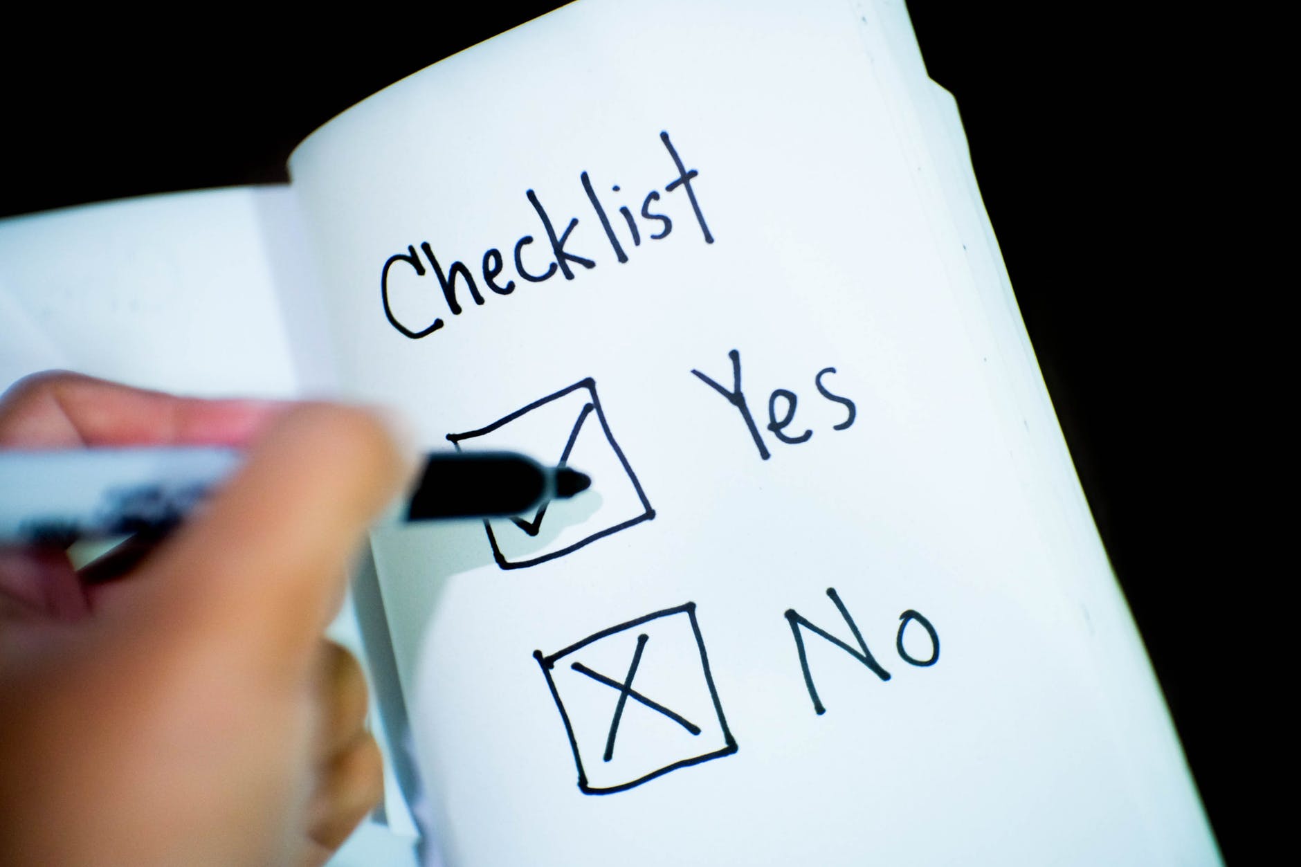 Hand checking the yes box in a yes/no checklist