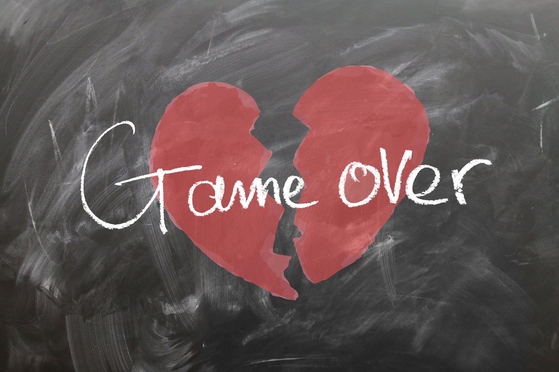 Broken heart and the words game over on a chalkboard
