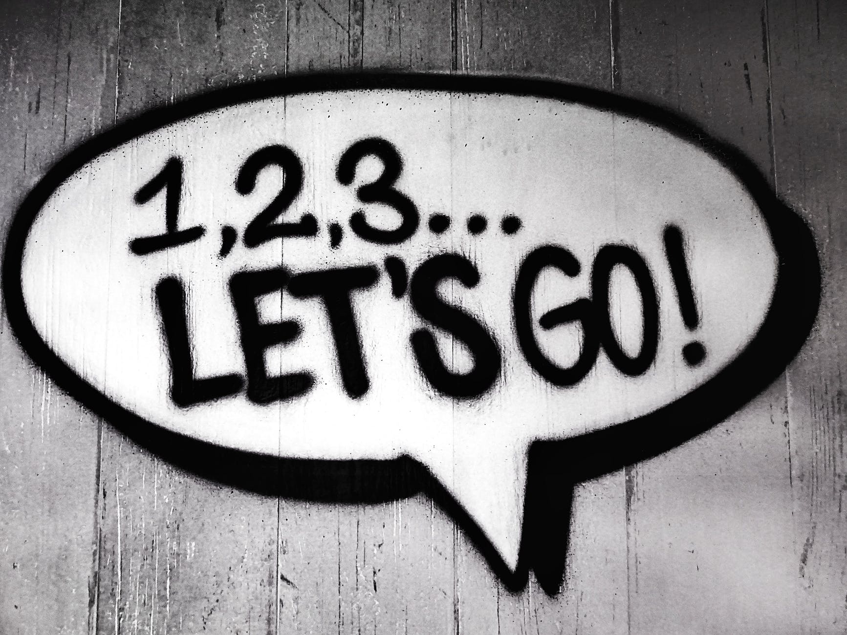 Speech bubble spray painted on wooden fence with '1, 2, 3 let's go' inside it 