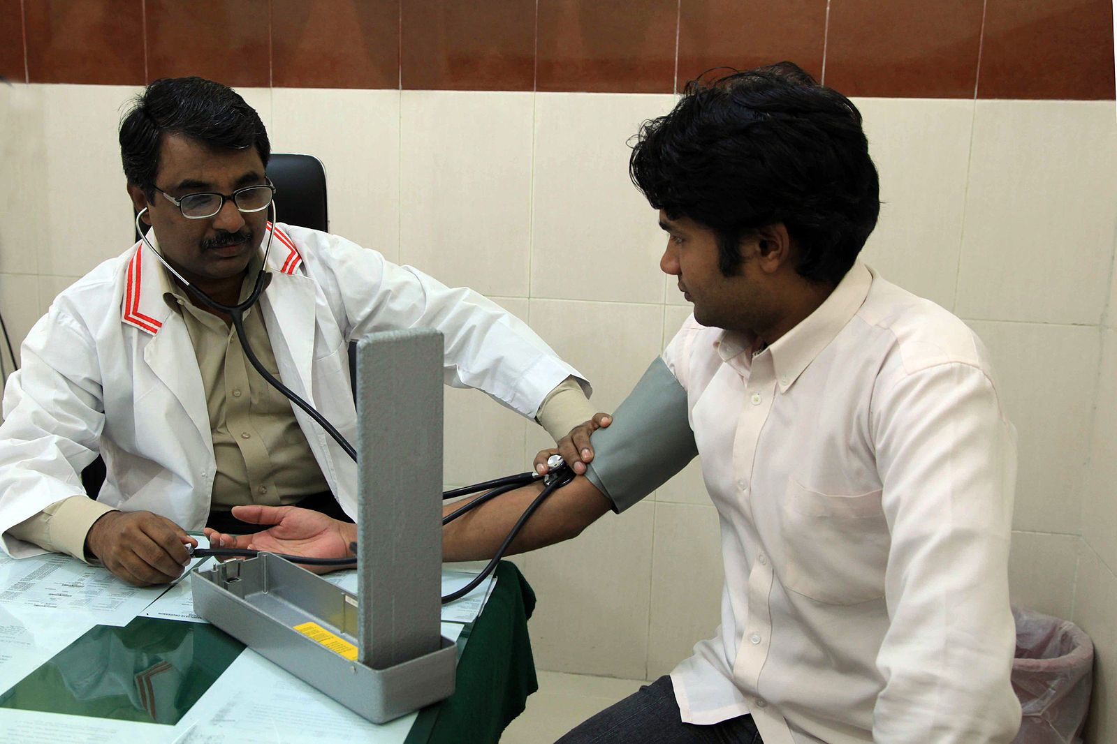 Doctor with a stethoscope testing a man's blood pressure