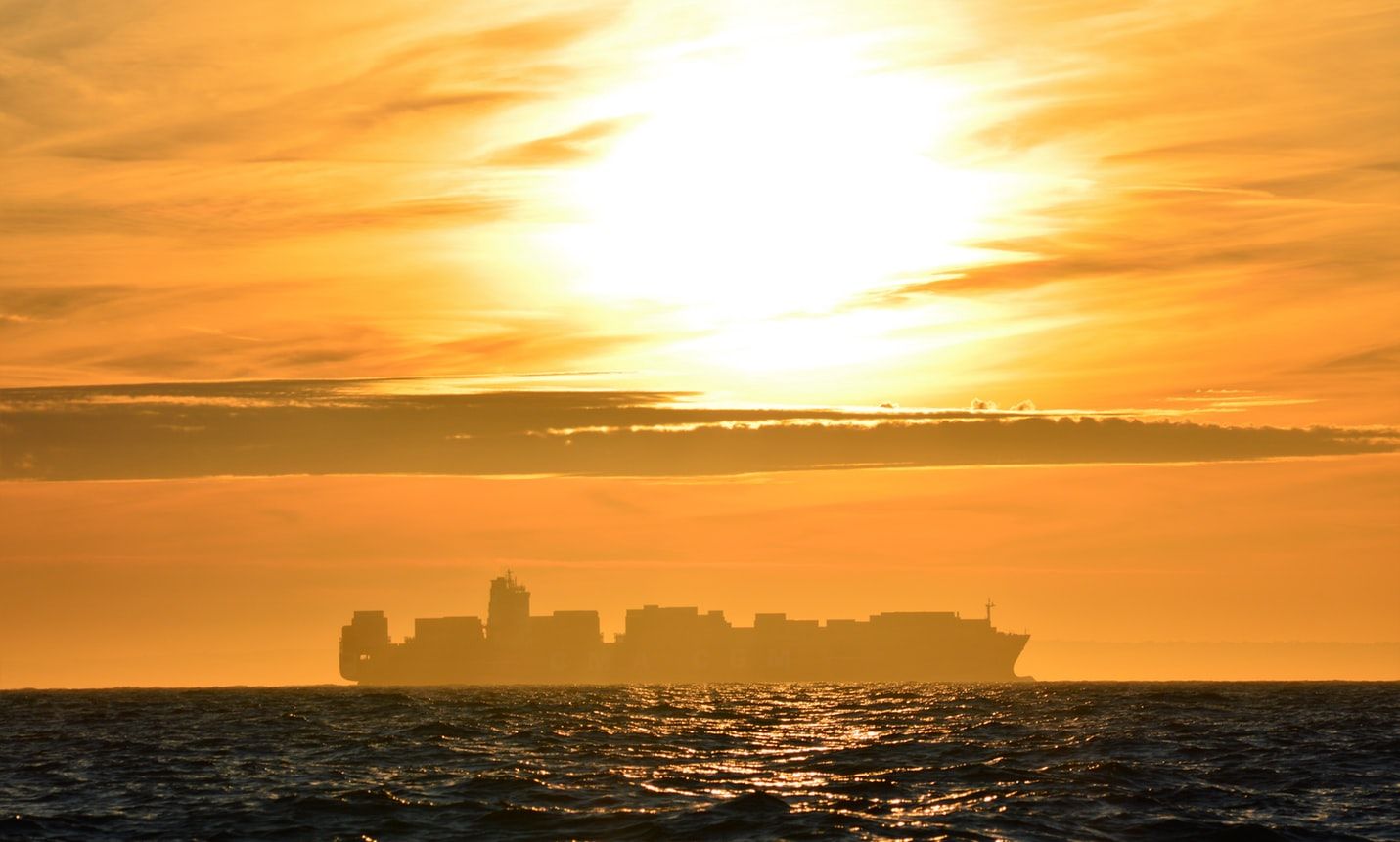 Silhouette of container ship at sunset