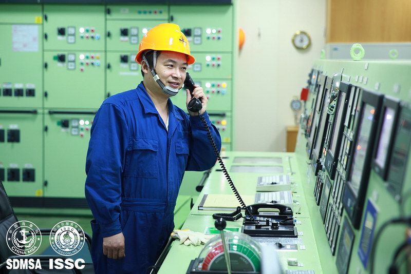Seafarer in overalls and hard hat on the phone in a control room