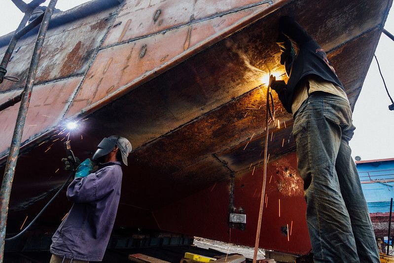 Men welding the hull of a vessel