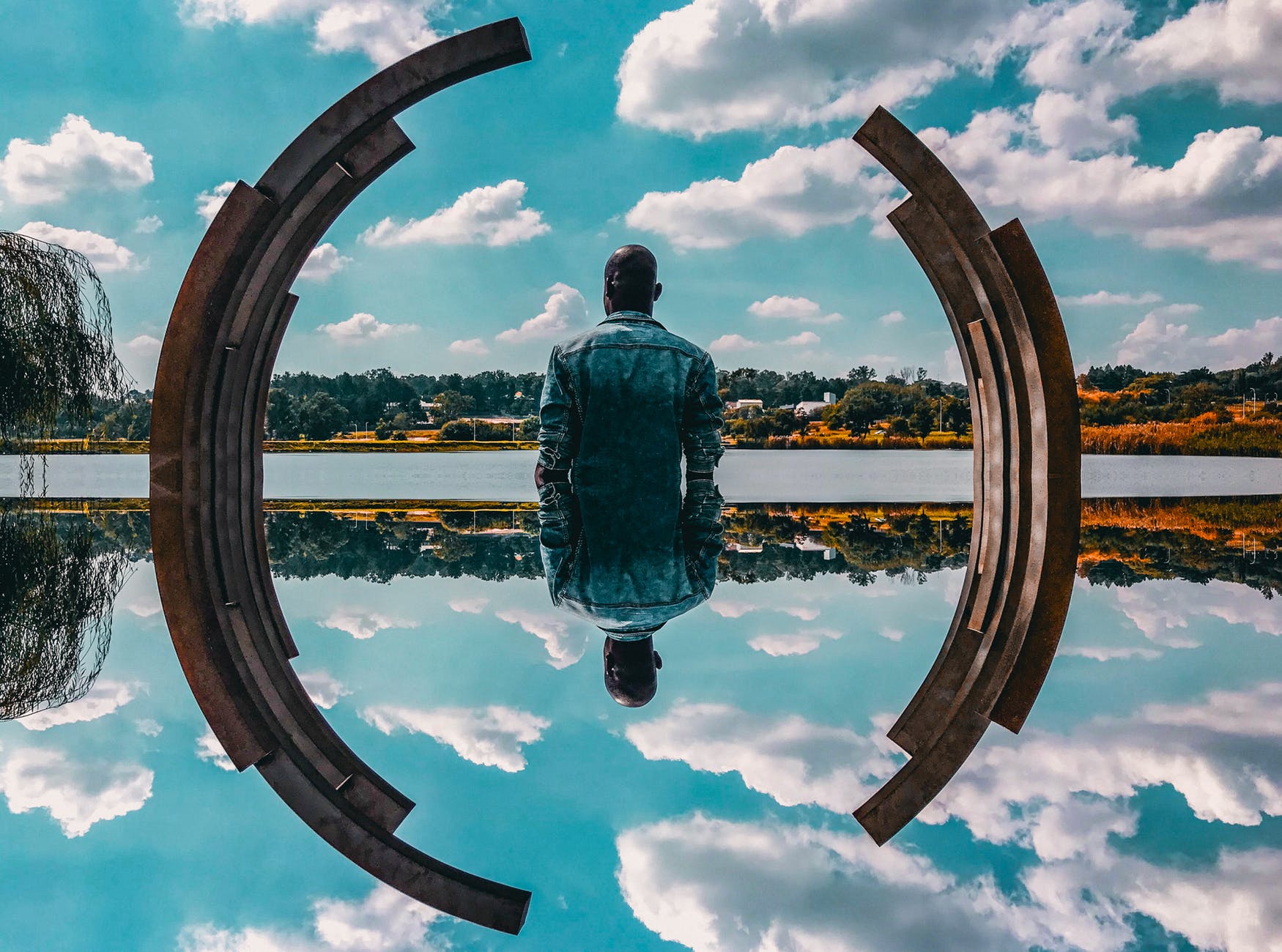 Reflection of a man gazing at clouds reflected in water