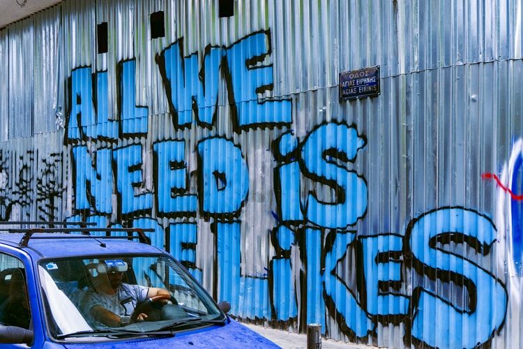'All we need is likes' spray painted on a metal sheet