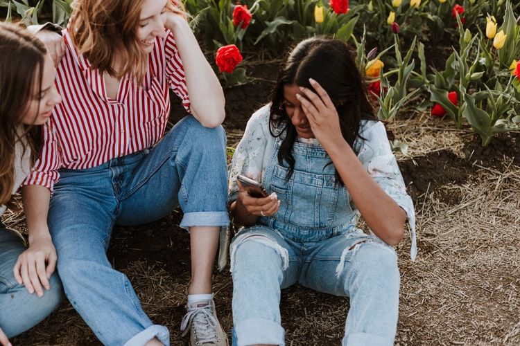 Three young women with one looking at her phones