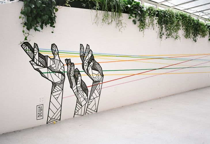 Wall art depicting hands holding colored string