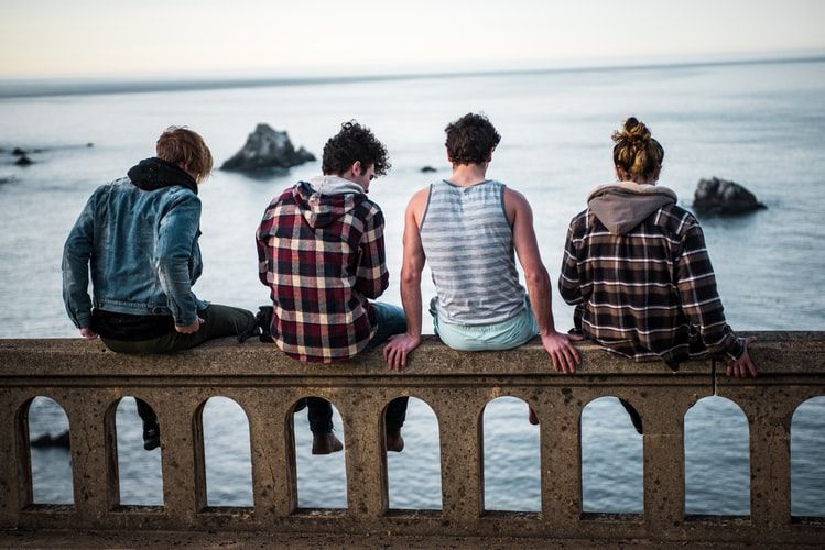 Group of friends sitting on a wall looking at the ocean