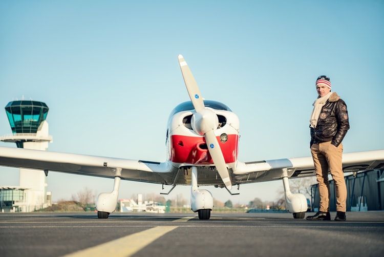Man in pilot jacket standing next to plane