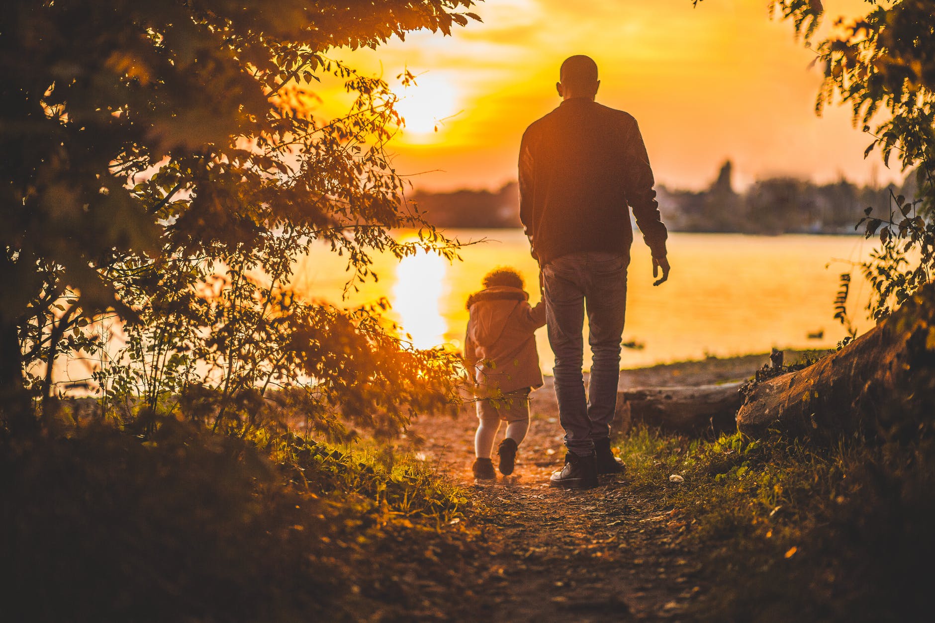 Man and small child by a lake at sunset