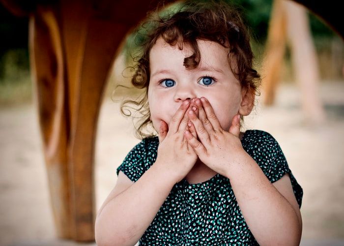 Little girl with her hands over her mouth