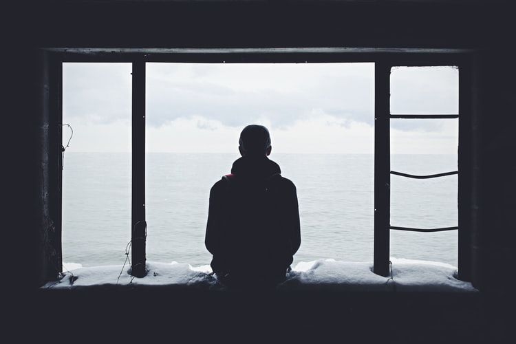 Man looking through window and staring at the sea