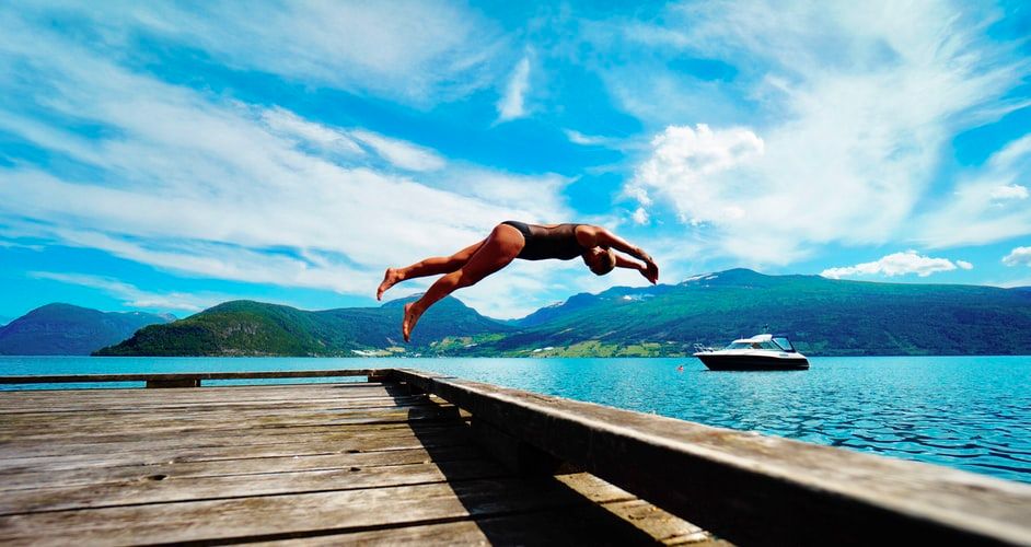 Person diving into a lake from a dock