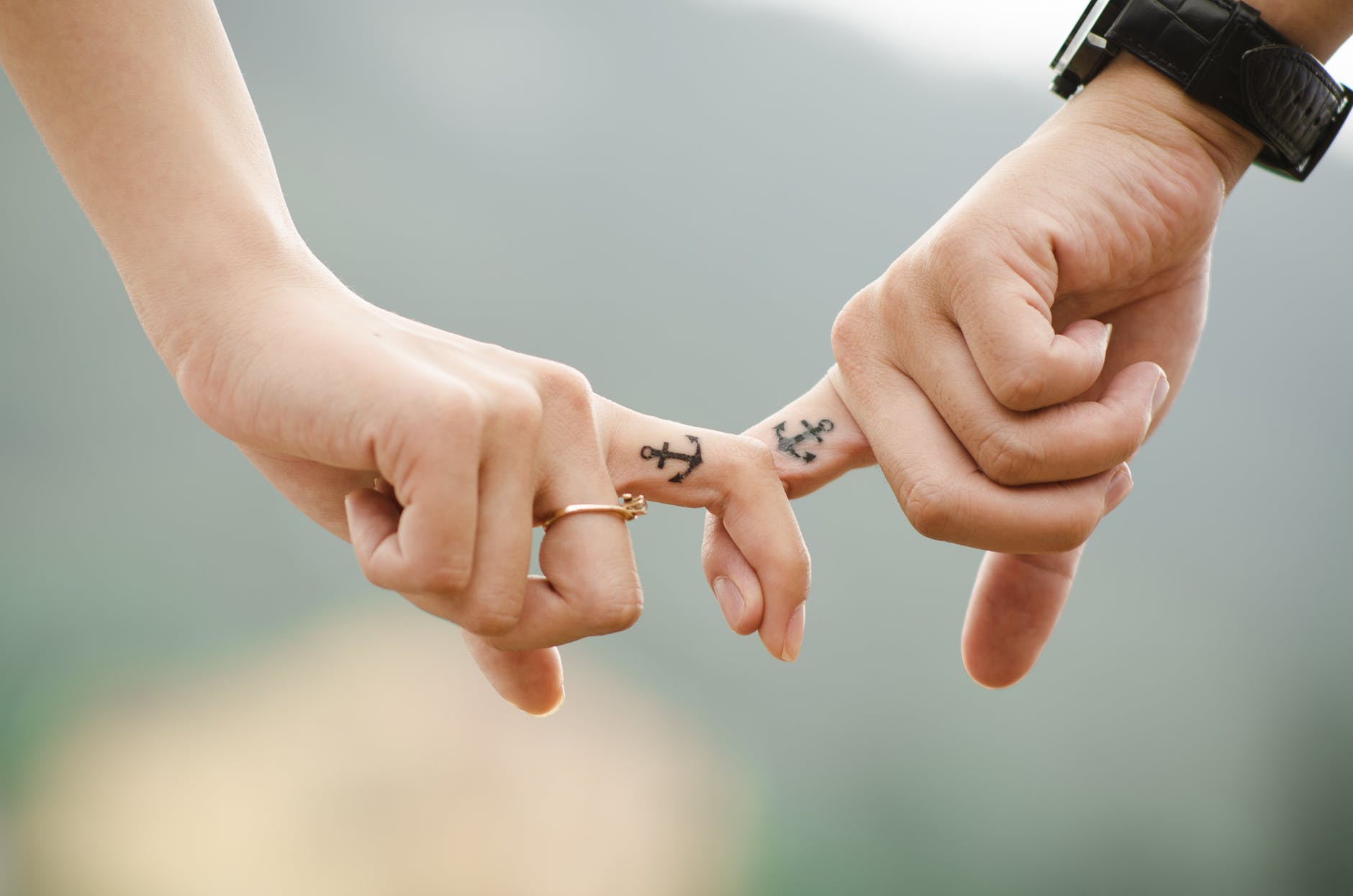 Couple with anchor tattoos linking fingers