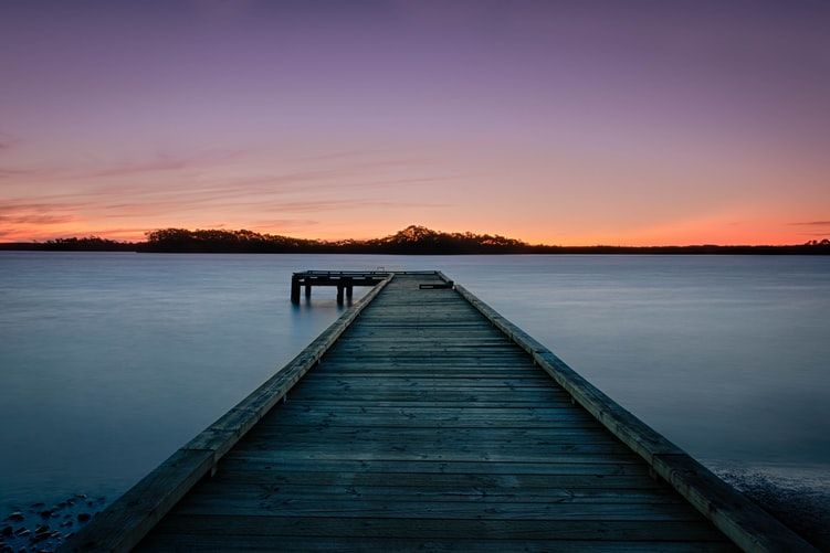 A dock stretching out into a lake at sunset