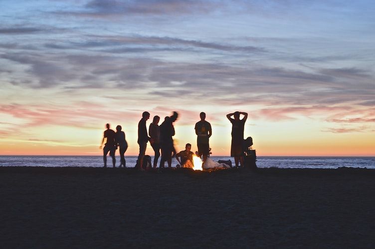 Group of people on the beach at sunset having a campfire