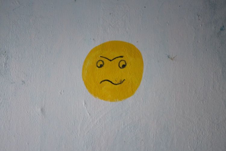 Frowning face emoji painted on a wall