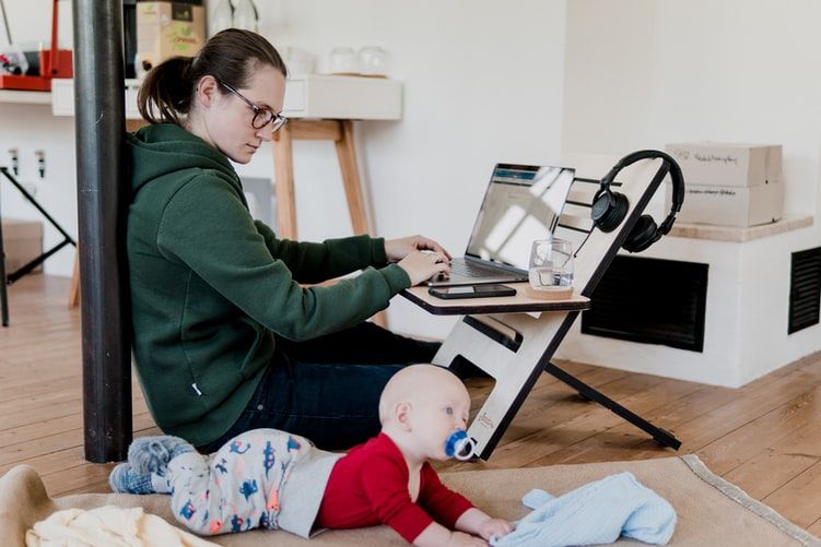 Woman working from home while trying to look after a baby