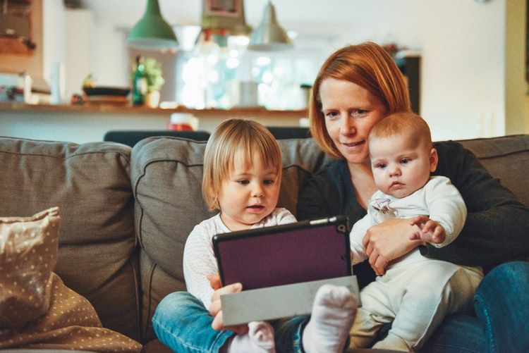 Mom and two young kids looking at a tablet PC