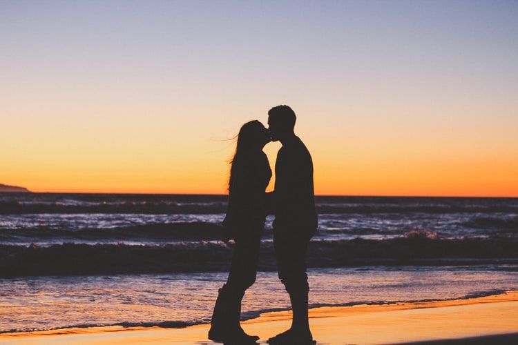 Couple kissing on a beach at sunset