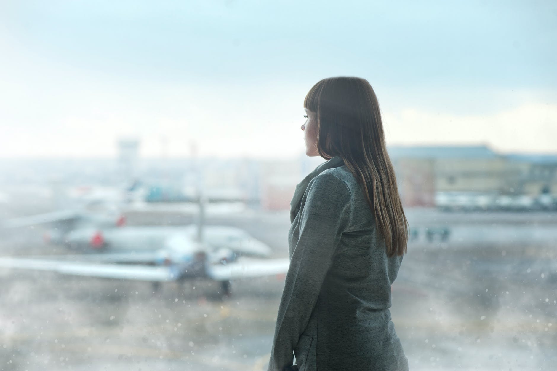 Woman gazing out of an airport window at planes