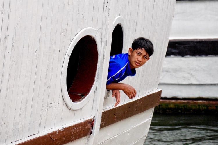 Boy hanging out of a ship's porthole 