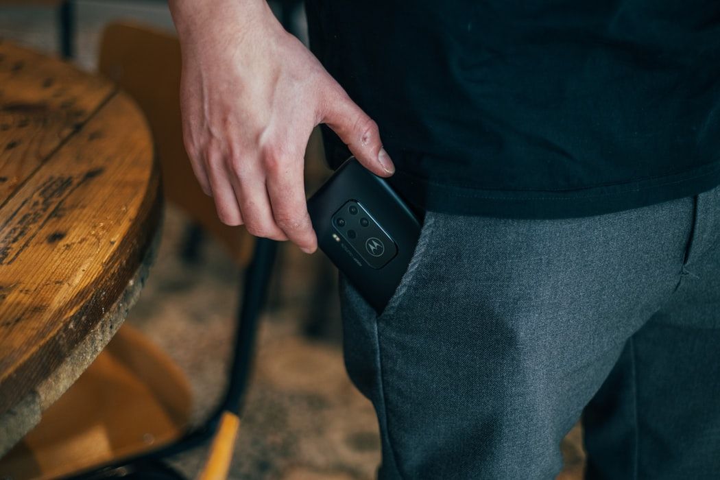 Man's hand pulling a phone out of his jeans pocket