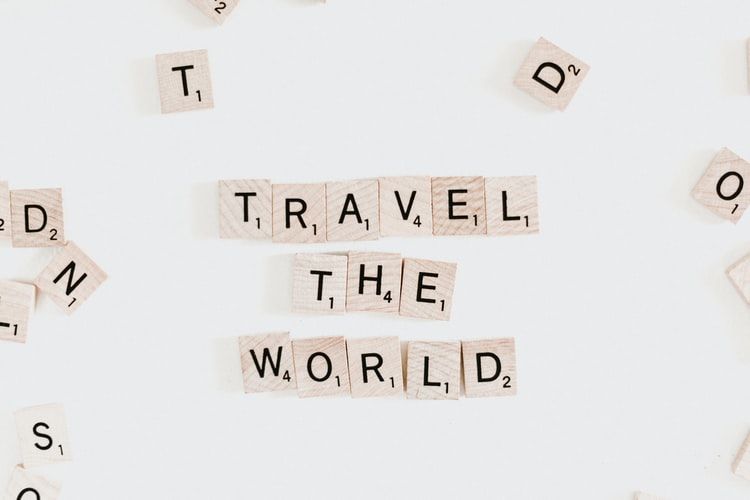 Scrabble tiles spelling out 'travel the world'