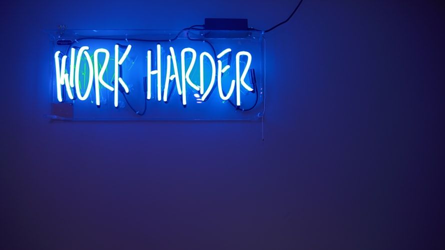 Blue neon sign saying 'work harder'