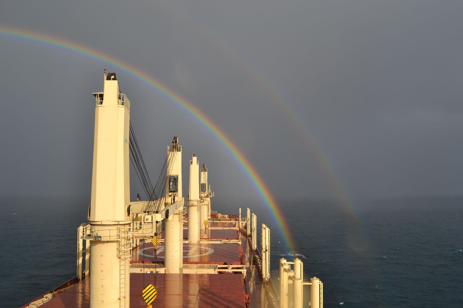 View from the bridge of a bulk carrier as it sails towards a rainbow
